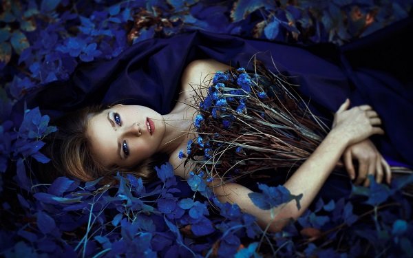 Девушка с букетом синих ирисов на ковре из листьев