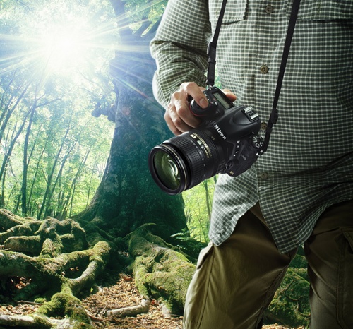 Полнокадровая камера Nikon D750 с универсальным объективом в руках фотографа.