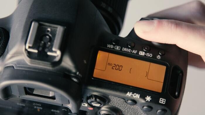 A close up of changing camera ISO settings on a DSLR