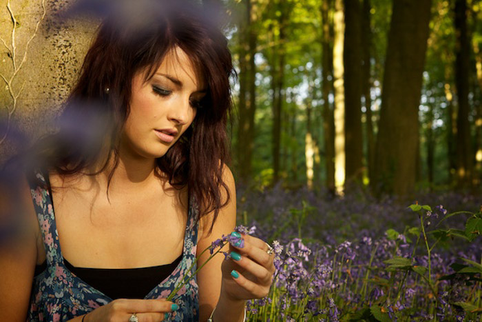 An outdoor portrait of a female model holding purple flowers