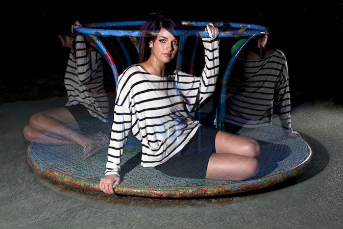 A long exposure night portrait of a female model posing on a merry go round