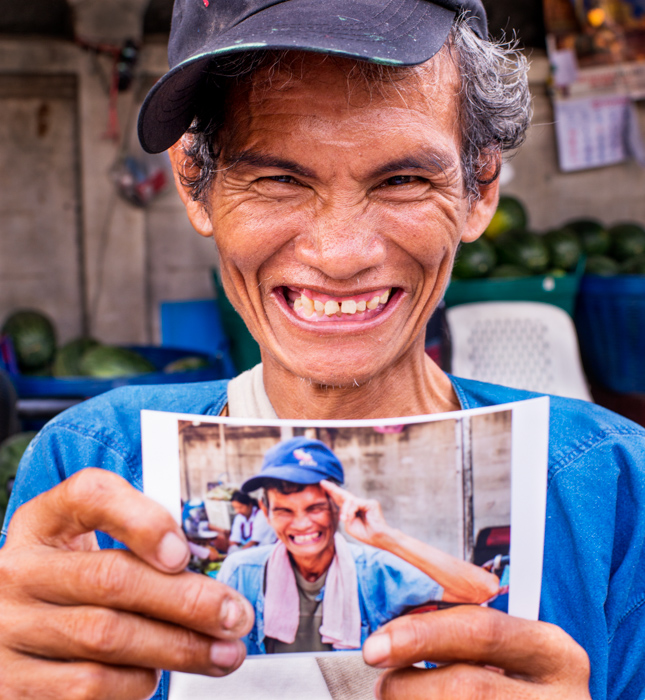 A market porter holding a picture of himself in Chiang Mai, Thailand, documentary photography
