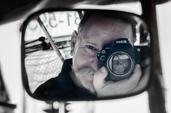 The photographer taking a selfie through a car mirror. Documentary photography. 