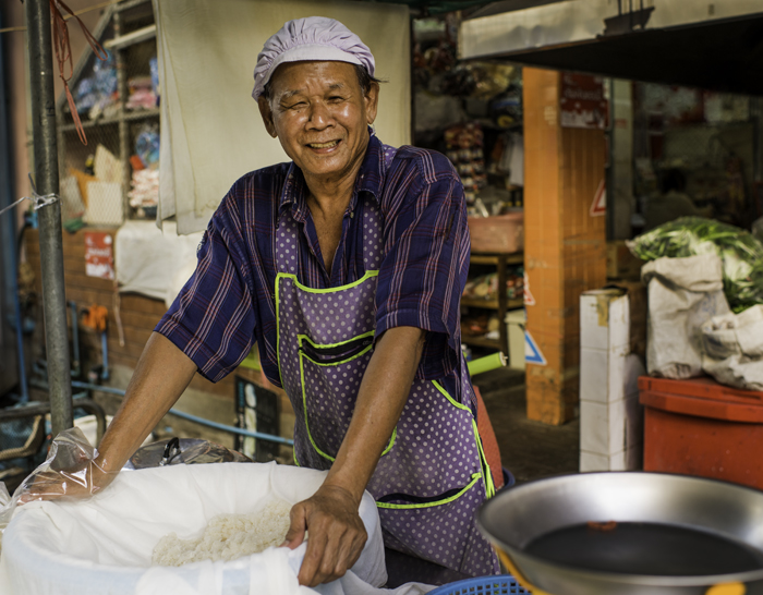 Documentary photography portrait of a sticky rice vendor at Muang Mai Market, Chiang Mai, Thailand