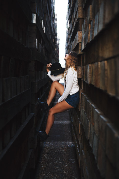 Cool editorial style portrait of a girl standing between two walls, people posing in photographs