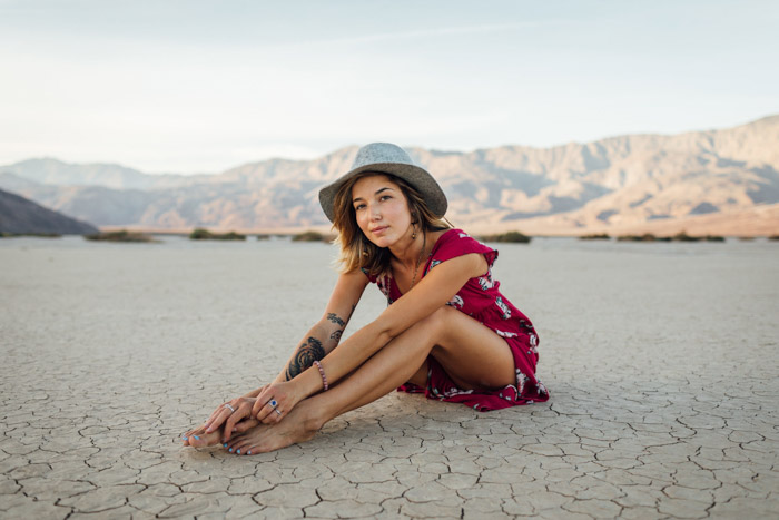 Bright portrait of a girl sitting on a desert ground, posing people in photographs