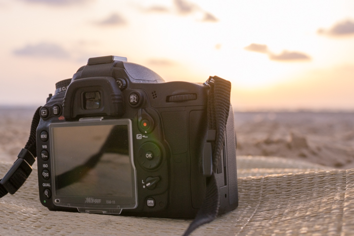 A DSLR photography camera resting on cloth at the beach 