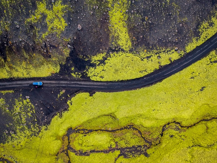 Aerial shot of a blue car on a road 