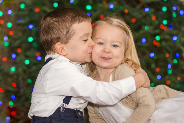 Two young children embracing with blurred background of Christmas lights