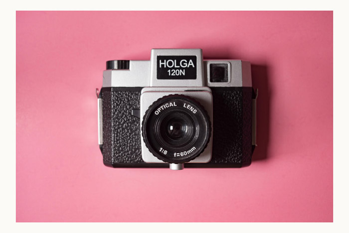 A holga camera on pink background with a white photoshop border