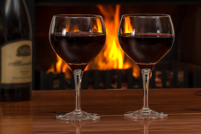 A photo of a bottle of wine and two glasses with a fire in the background, the result of using gaussian blur in photoshop 