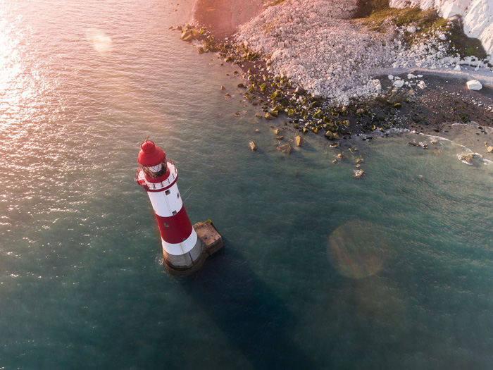 Overhead photo of a lighthouse on a coast with lens flare