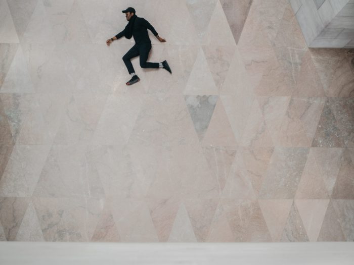 Photo of a guy seemingly jumping with a marble floor background 