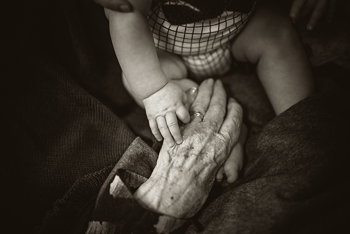 A babys hand touching an old person hands