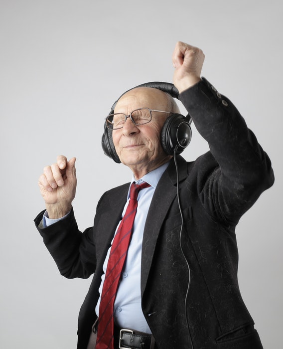 An old man wearing headphones and dancing