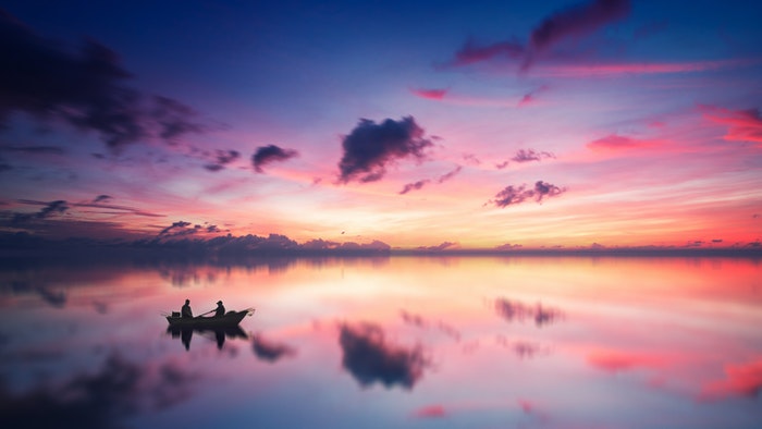 Colorful clouds above a lake with the silhouette of a boat