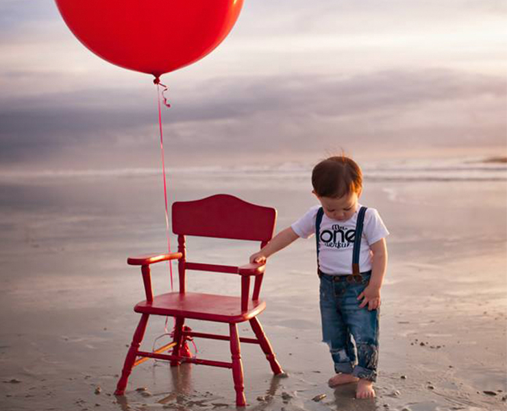 baby on beach with red balloon